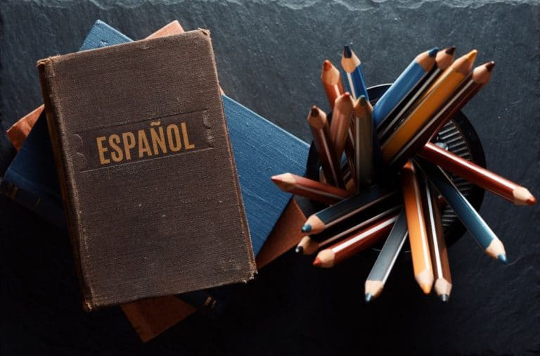 Spanish notebook next to a collection of colored pencils