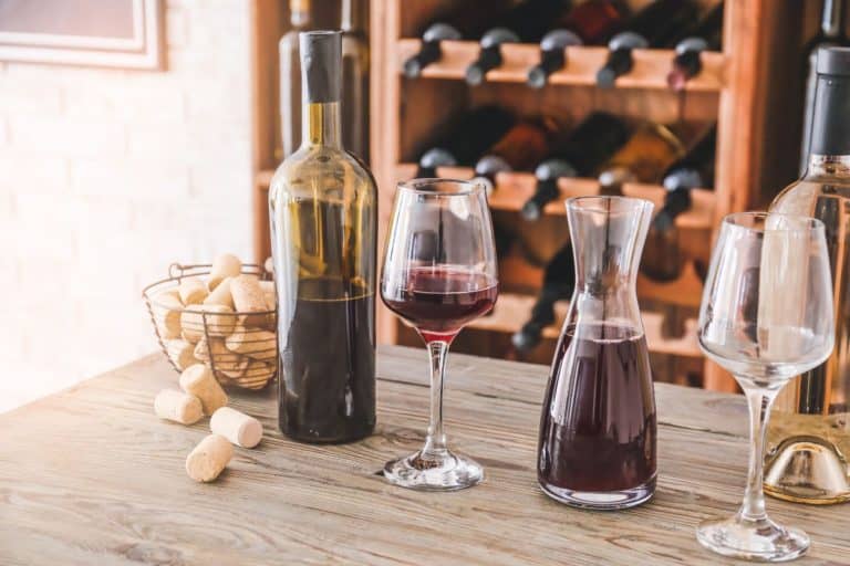 Red wine bottle next to a filled wine glass and carafe