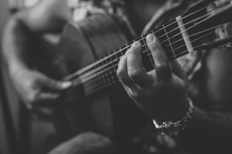 A close up of a musician in a small town playing the acoustic guitar