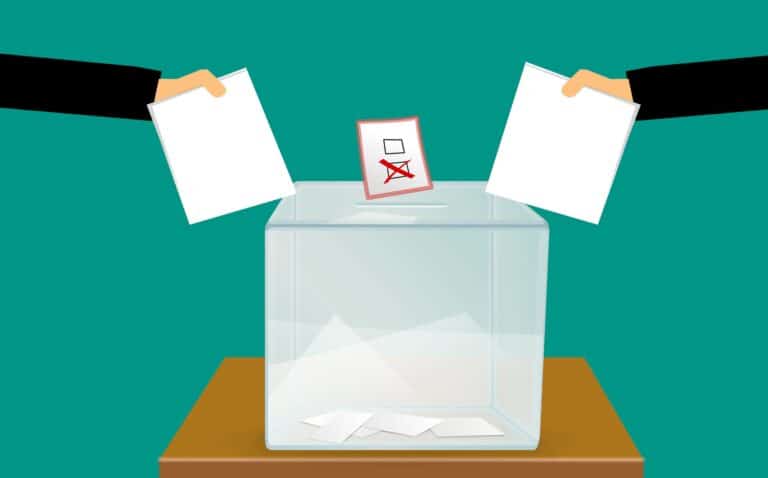 Two people drop their ballots into a ballot box during midterm elections