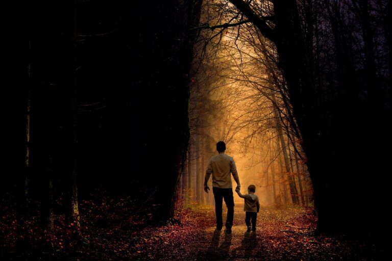 A father and son walking on a trail in the woods