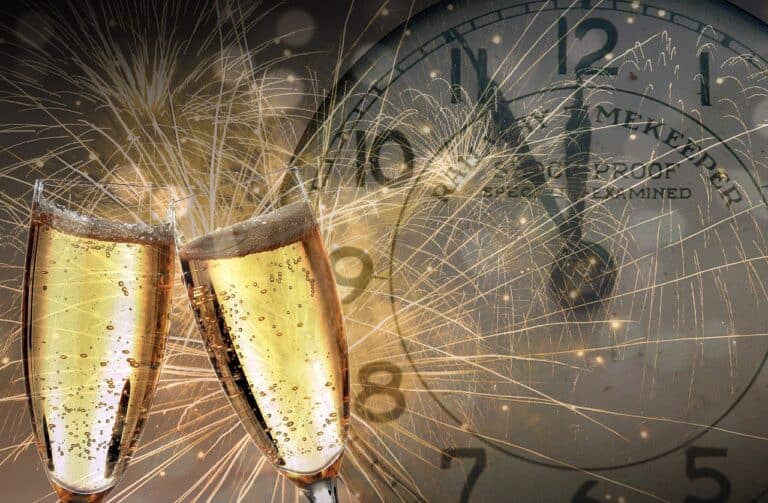 Two champagne glasses toasting to a Happy New Year in front of a clock