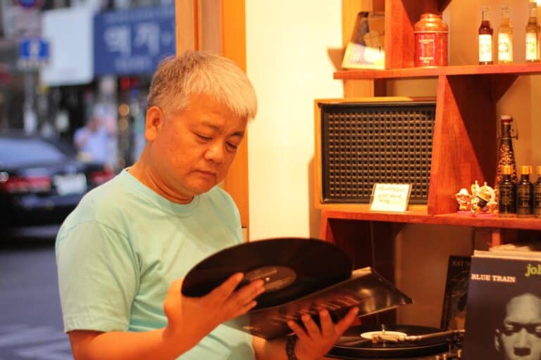 An older hipster looking at vinyl, probably wearing dad shorts